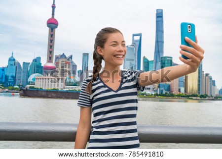 China travel Asian girl tourist taking phone selfie photo on the Bund in Shanghai city vacation. Happy chinese young woman using smartphone app vlogging posting on social media. Multiracial person.
