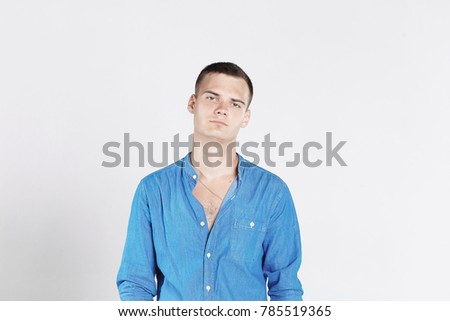 Studio shot of young man looking at the camera. Isolated on white background. Horizontal format, he has a serious face, he is wearing a blue T-shirt.