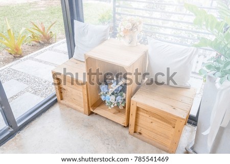 Two pillows on wooden desk with wooden stool and flower vases