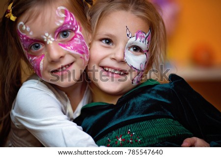 Funny cute little girls with painting faces are hugging ang having fun. Royalty-Free Stock Photo #785547640