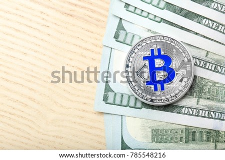 Silver bitcoin with dollar bills on table