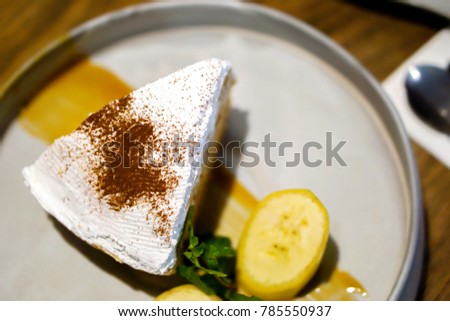 Top view of Banana Banoffee pie with bananas slice and peppermint leaves on gray ceramic plate and wooden table background.