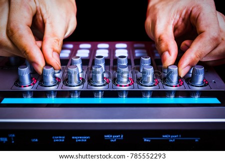 male sound engineer hands tuning knobs of studio gears, digital sound mixer, pre-amp, audio interface, effect signal processor for TV radio broadcasting, post production or music background