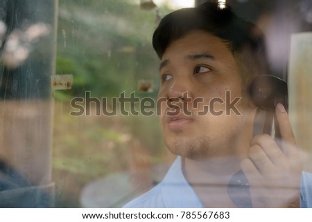 Portrait of young Asian businessman using the payphone outdoors Royalty-Free Stock Photo #785567683