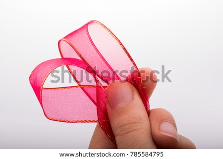 Hand holding a pink color ribbon in hand