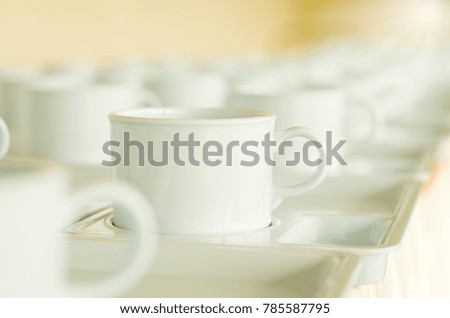 Empty Cups of coffee or tea on plate in rows service coffe or tea in break time on seminar with blurred background, warm light