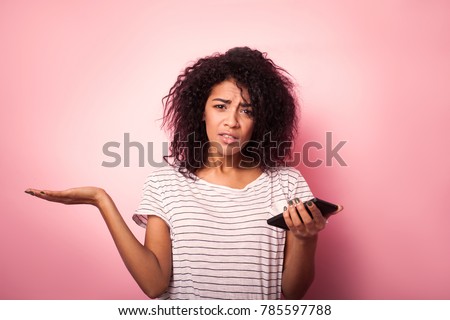 Young woman with mobile phone confused isolated on pink backgrou Royalty-Free Stock Photo #785597788