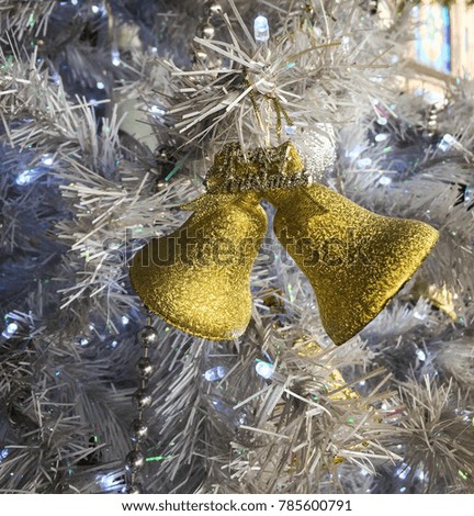 Christmas decorations with golden bells on the white fir tree.