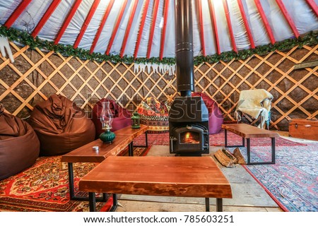 cozy yurt camping interior with fireplace inside. Authentic glamping territory. Royalty-Free Stock Photo #785603251