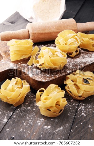 Making homemade pasta linguine on rustic kitchen table with flour, rolling pin and pasta