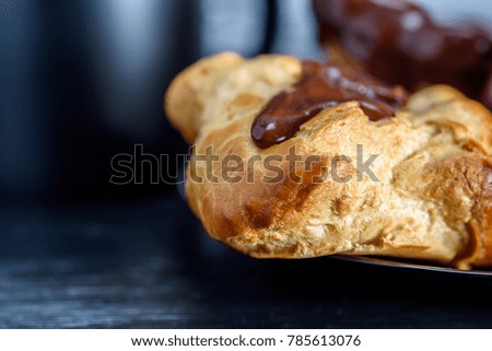 Coffee and chocolate eclairs on a dark wooden background