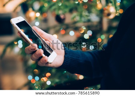 man relaxing at home with smartphone in his hand, cozy holiday e
