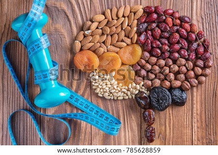 Human brain is made of dried apricots and nuts with measuring tape and dumbbell on a wooden table. Brain made of a nuts and dried apricots. Concept of healthy food and healthy lifestyle.  Royalty-Free Stock Photo #785628859