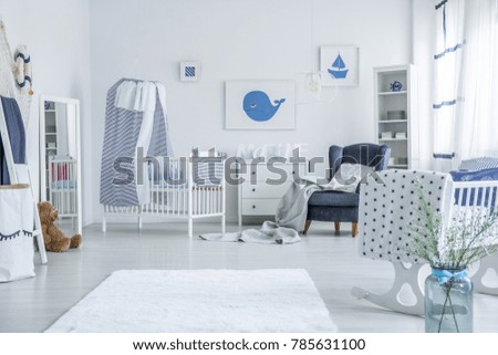 White crib with striped veil standing against white wall next to a chest of drawers in room for a child