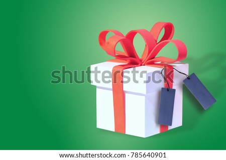 White gift box and red ribbon with blank card on green background, celebration concept