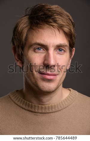 Studio shot of handsome man wearing brown shirt against gray background