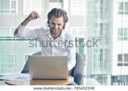 Happy western businessman using a laptop in living room