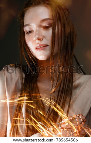 A young girl with red hair and with a luminous garland. Beautiful model with shining bulbs and lights. Gentle makeup. Festive new year's image. Beauty of the face. Photo is taken in the studio.