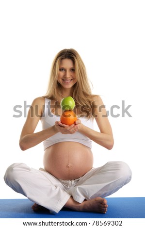 Pregnant woman practicing yoga and keeps fruit isolated on white
