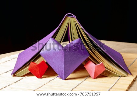 Symbol of love and Valentine's Day on the background of notebook. Paper hearts are red, pink and ultraviolet colors.