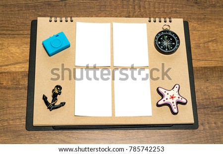 Small blank white sheet on brown paper with blue camera, anchor, compass and star fish magnet
