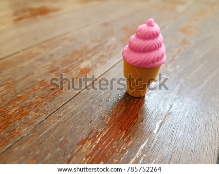Tiny cute rubber of pink ice cream cone on wooden background