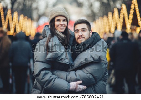 Couple holding hands walking on city christmas market looking for presents