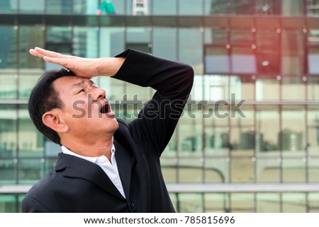 Businessman is with his hands on forehead and very worried. Do not know what to do. on urban background