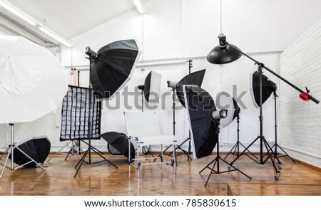 Professional photo studio with lighting equipment; light stands, softbox, studio flash, umbrellas.