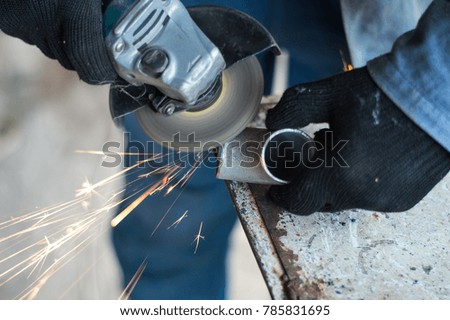 A man is working a metal pipe with a tool for cutting metal