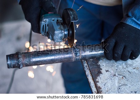 A man is working a metal pipe with a tool for cutting metal