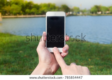 Man hand holding mobile phone in park, close up, concept to use internet, line, messenger outdoor