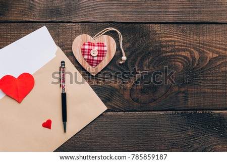 blank white sheet in an envelope on a wooden table, next to it is a ballpoint pen. declaration of love on St. Valentine's Day