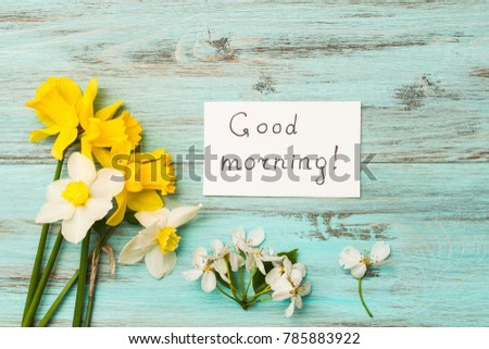 Spring flowers and an inscription with a good morning. Narcissus on a wooden background. The concept of the beginning of the day