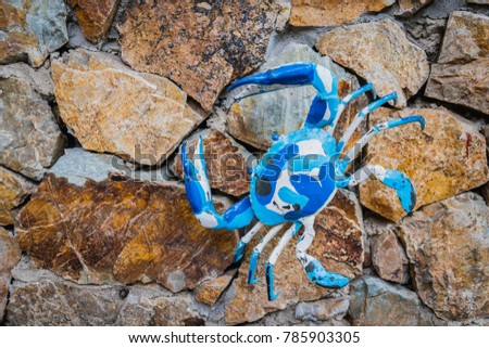 Blue crab sculpture on rock wall