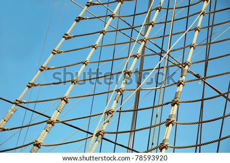 Ropes of sailing boat against blue sky as sea transportation background