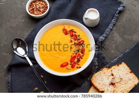 Pumpkin soup in white plate with spice on dark background. Top view