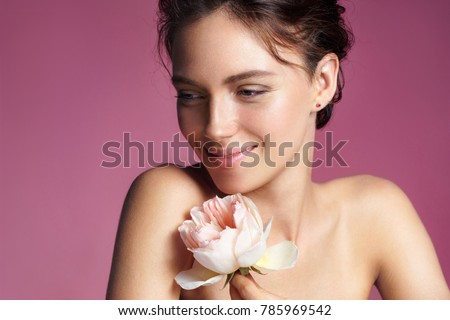 Charming young woman with perfect makeup. Photo of brunette woman with rose on pink background. Skin care concept
