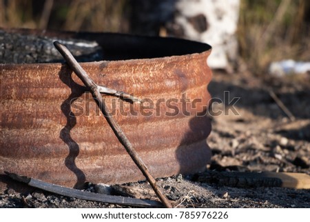 Fire poker resting against rusted metal firepit