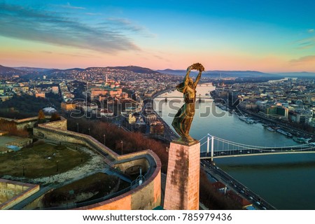 Budapest, Hungary - Aerial skyline view of Statue of Liberty with Buda Castle Royal Palace and Chain Bridge at background. Morning sunrise with blue sky and clouds Royalty-Free Stock Photo #785979436
