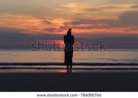 beautiful Woman Stand alone lonely by the sea.Sunsets Silhouette style