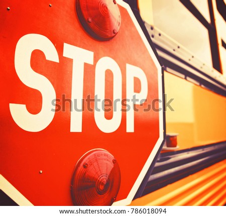  wide angle front view of a bright yellow orange school bus and the big red stop sign 
