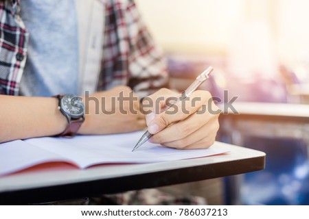 soft focus.high school or university student holding pencil writing on paper answer sheet.sitting on lecture chair taking final exam attending in examination room or classroom.student in casual Royalty-Free Stock Photo #786037213