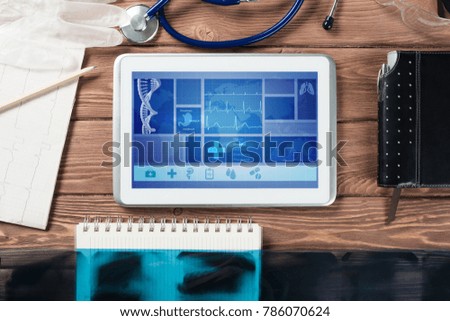 White tablet pc and doctor tools on wooden table