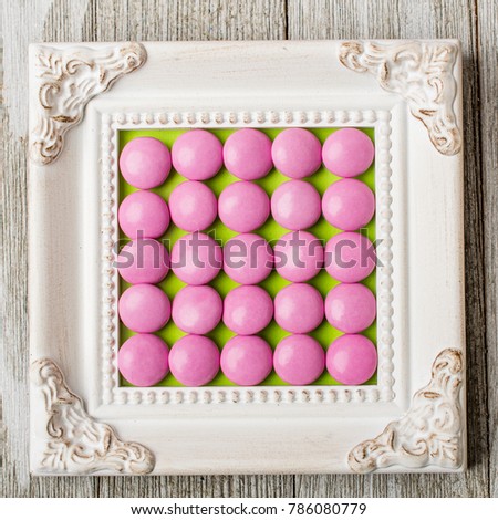 Vintage frame with pink round candy arranged in the center.