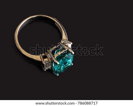 Closeup green gem ring with white diamond on black background