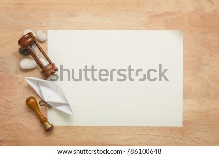 Blank paper with hourglass, paper boat, stamper, small key and stones on wood table, Vintage Background concept