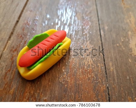 Tiny cute rubber of Hot dog on wooden background