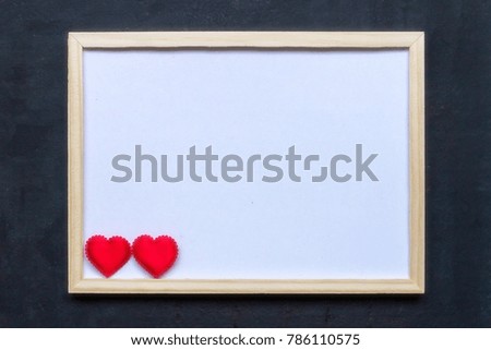 Two red hearts and whiteboard on black background, classical soft focus