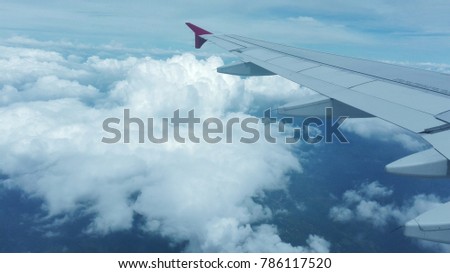 A picture from a plane in the sky and a wing of a plane covered with sunlight and visible below